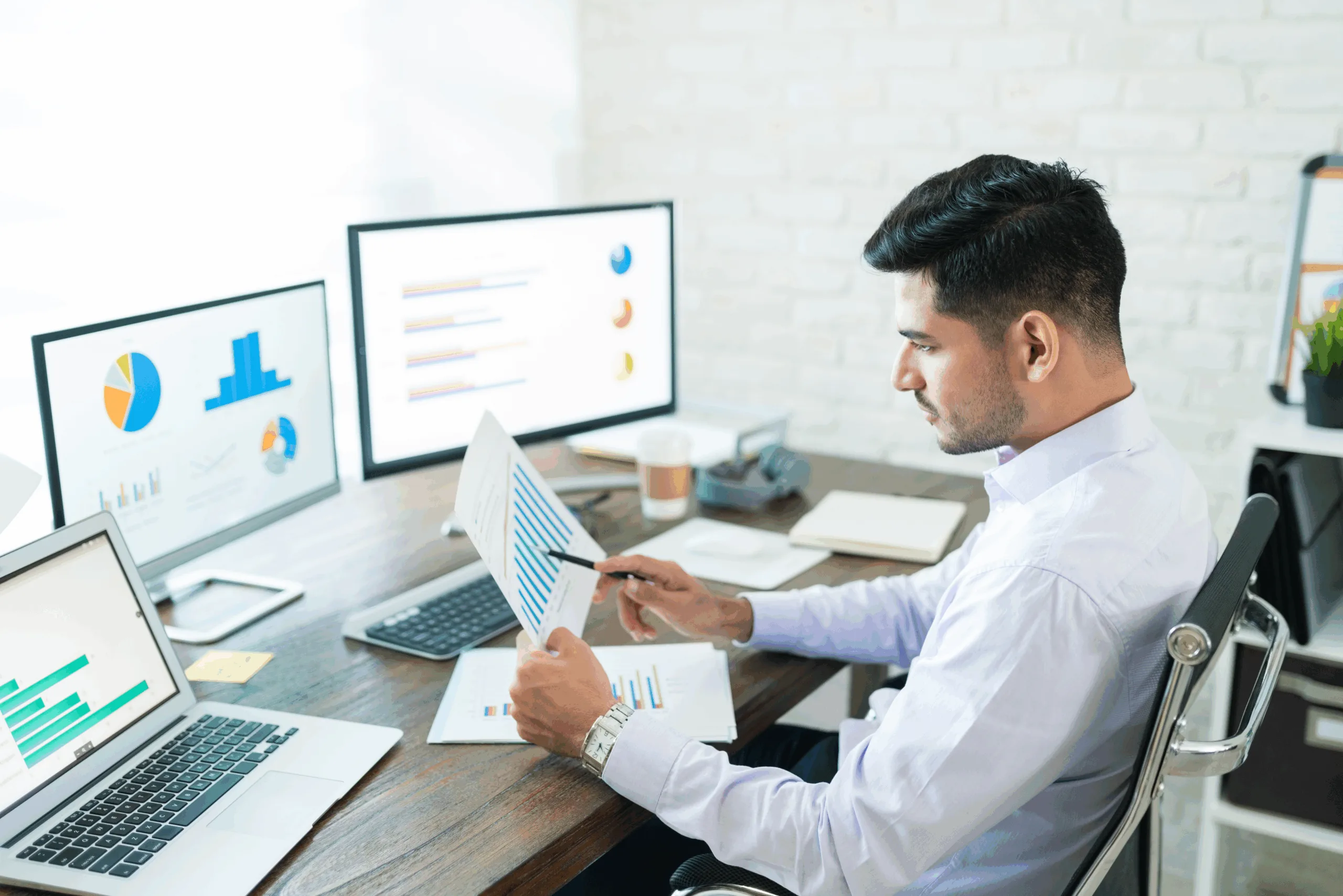 Marketing analyst reviewing sales data and performance charts on multiple screens during a mid-year marketing audit – Australia-based strategy review