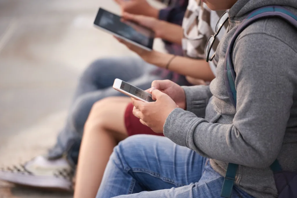 Group of young people using smartphones and tablets, highlighting the need for a mobile-first website strategy in today’s changing economy.